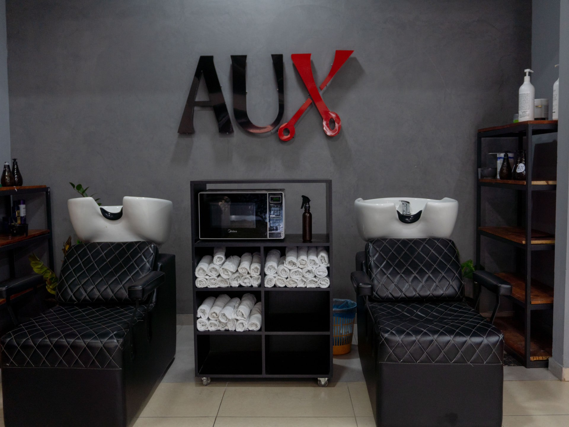 Área de lavagem da AUX Barbearia com o letreiro da marca na parede