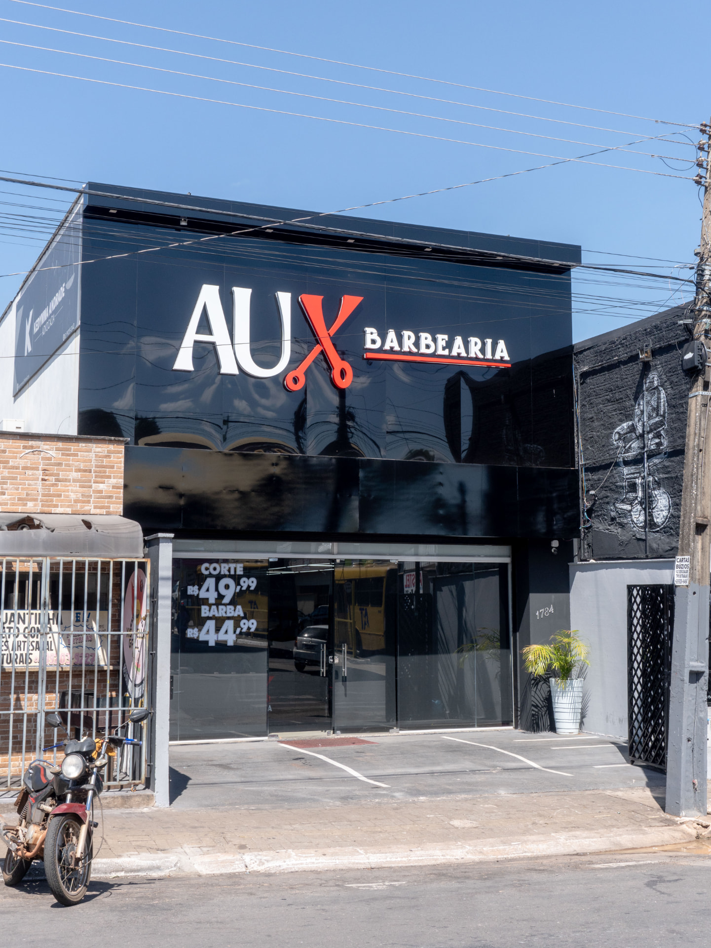 Fachada da AUX Barbearia com letreiro iluminado